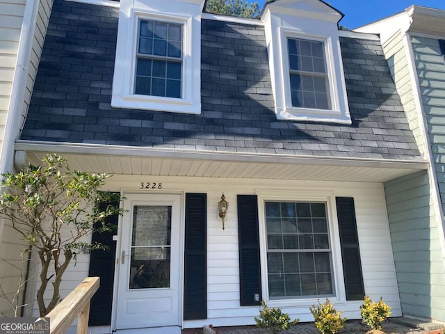 property entrance with a porch and roof with shingles