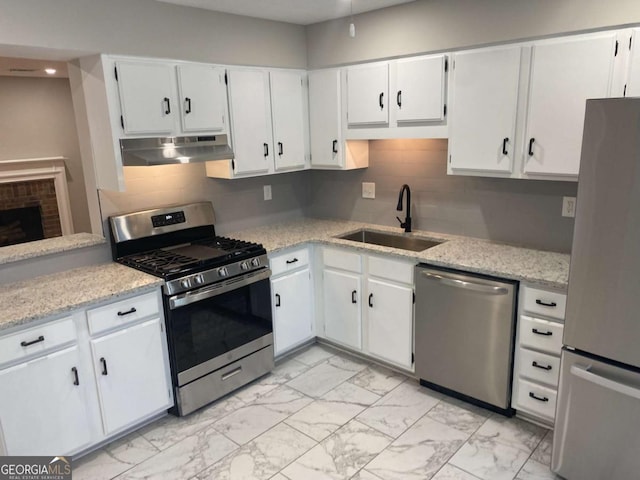 kitchen with marble finish floor, stainless steel appliances, a sink, and under cabinet range hood