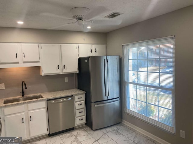 kitchen featuring marble finish floor, white cabinetry, appliances with stainless steel finishes, and a sink