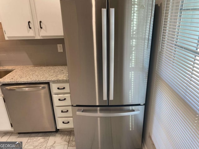 kitchen featuring light stone counters, marble finish floor, decorative backsplash, appliances with stainless steel finishes, and white cabinets