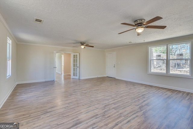 spare room featuring ornamental molding, light wood-type flooring, and visible vents