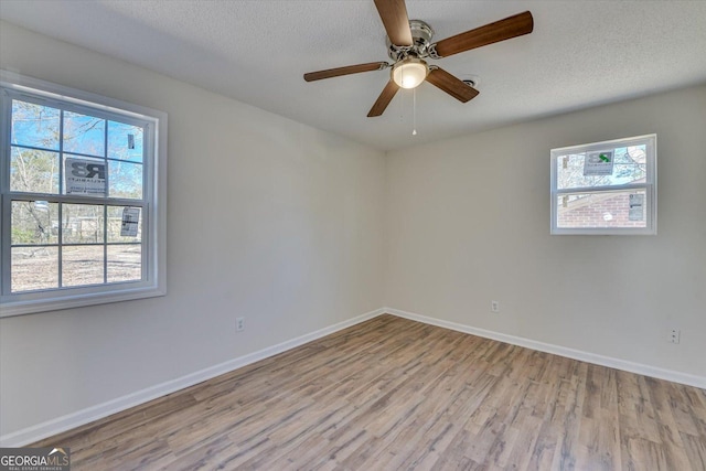 empty room with a textured ceiling, ceiling fan, wood finished floors, and baseboards