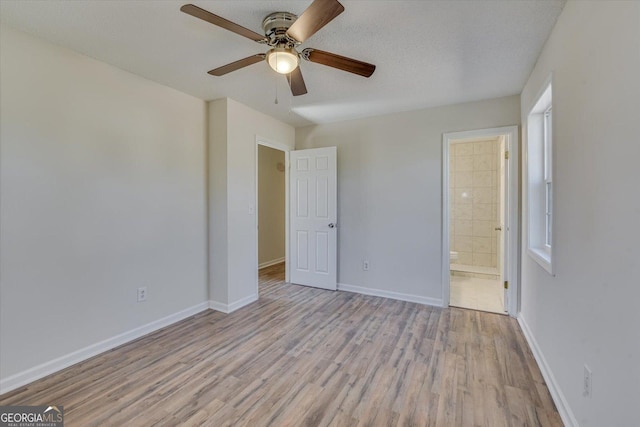 unfurnished bedroom featuring a textured ceiling, wood finished floors, a ceiling fan, baseboards, and ensuite bath