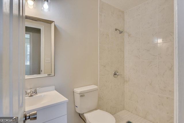 full bath featuring toilet, a tile shower, and vanity