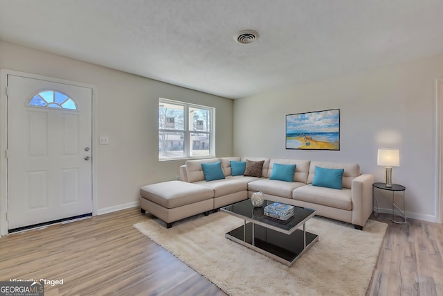 living room featuring light wood-style floors, baseboards, and visible vents