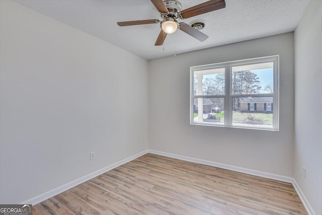 empty room featuring a textured ceiling, wood finished floors, visible vents, and baseboards