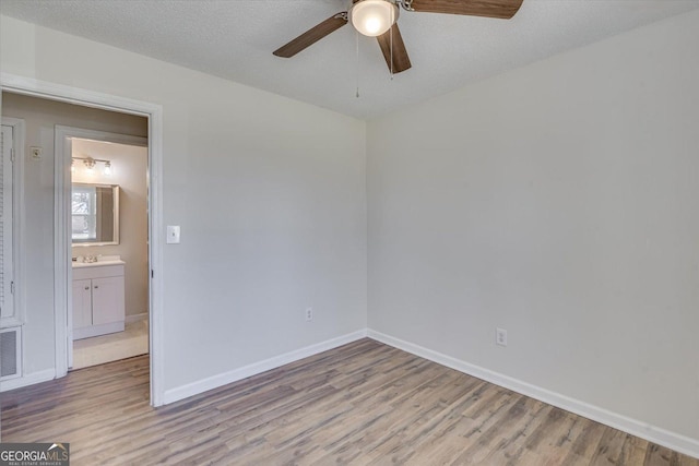 spare room with a textured ceiling, a ceiling fan, light wood-style flooring, and baseboards