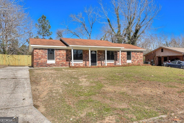 ranch-style house featuring brick siding, driveway, a front lawn, and fence