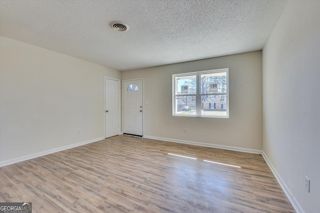 foyer with a textured ceiling, wood finished floors, visible vents, and baseboards