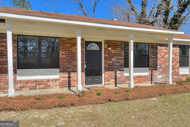 entrance to property with brick siding and a porch