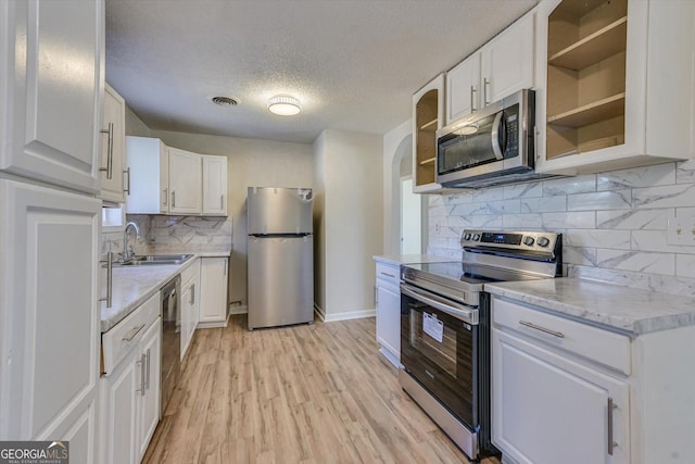 kitchen featuring open shelves, stainless steel appliances, visible vents, white cabinetry, and a sink