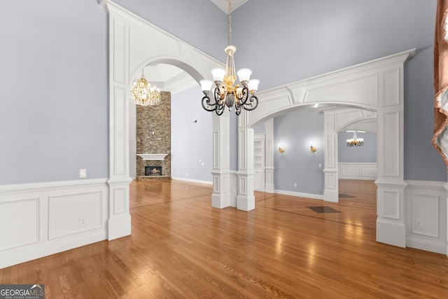 1348 Ewing Creek Dr, Dacula, GA 30019 - unfurnished dining area featuring a chandelier, arched walkways, wood finished floors, a decorative wall, and a fireplace