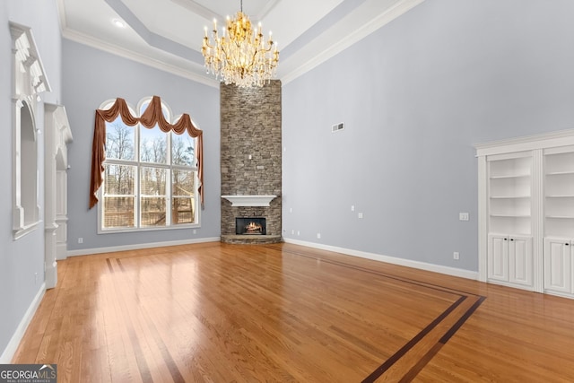 1348 Ewing Creek Dr, Dacula, GA 30019 - unfurnished living room featuring a chandelier, a towering ceiling, a stone fireplace, crown molding, and light wood-type flooring