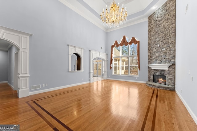 1348 Ewing Creek Dr, Dacula, GA 30019 - unfurnished living room featuring a towering ceiling, arched walkways, a fireplace, wood finished floors, and a chandelier