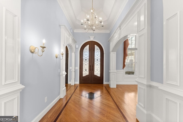 1348 Ewing Creek Dr, Dacula, GA 30019 - entrance foyer featuring light wood finished floors, a chandelier, french doors, arched walkways, and crown molding
