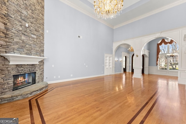 1348 Ewing Creek Dr, Dacula, GA 30019 - unfurnished living room with a high ceiling, a chandelier, wood-type flooring, arched walkways, and a stone fireplace