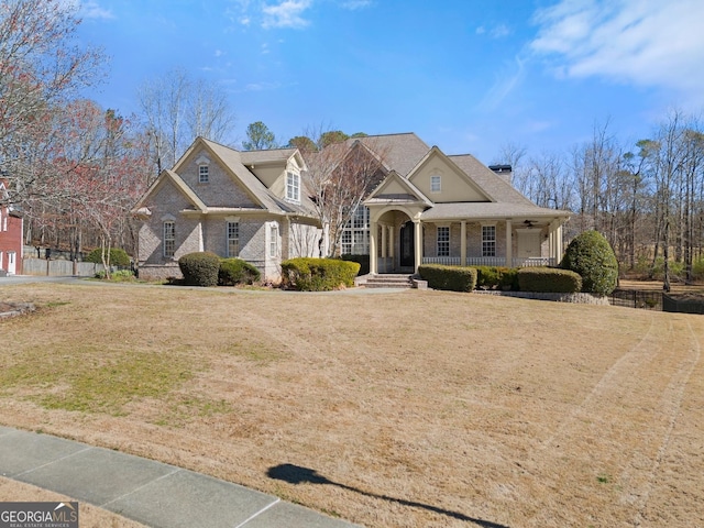 view of front of house with covered porch, ceiling fan, and a front yard