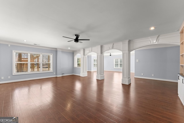 1348 Ewing Creek Dr, Dacula, GA 30019 - unfurnished living room with decorative columns, arched walkways, ceiling fan, dark wood-style flooring, and crown molding