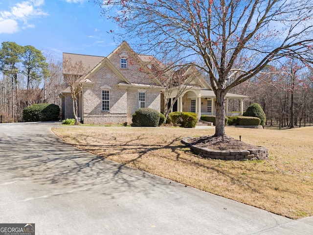 1348 Ewing Creek Dr, Dacula, GA 30019 - view of front facade featuring brick siding, a front yard, covered porch, and driveway