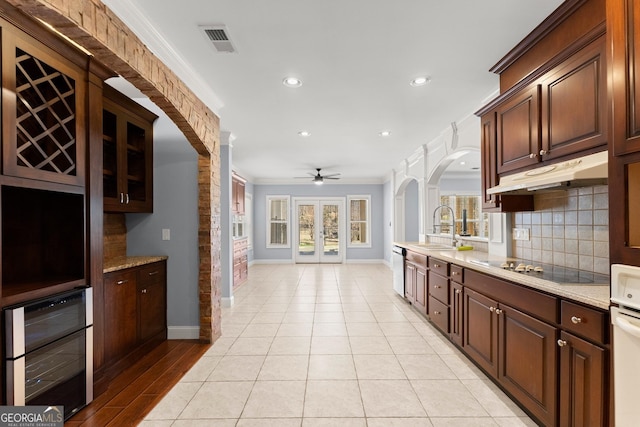 1348 Ewing Creek Dr, Dacula, GA 30019 - kitchen featuring arched walkways, crown molding, under cabinet range hood, recessed lighting, and wine cooler