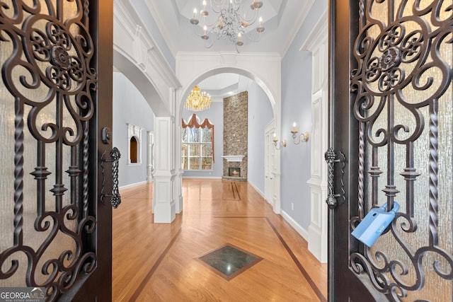1348 Ewing Creek Dr, Dacula, GA 30019 - entryway with arched walkways, a chandelier, light wood-style floors, crown molding, and decorative columns