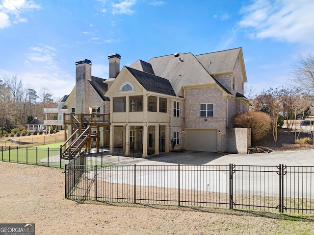 1348 Ewing Creek Dr, Dacula, GA 30019 - back of house with driveway, an attached garage, a fenced backyard, stairway, and brick siding