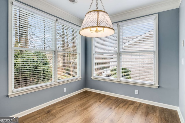 unfurnished dining area featuring ornamental molding, wood finished floors, visible vents, and baseboards