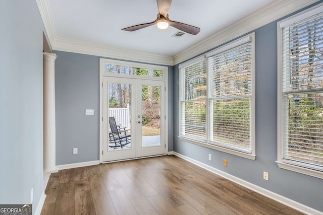 doorway to outside with wood finished floors, a ceiling fan, baseboards, decorative columns, and crown molding