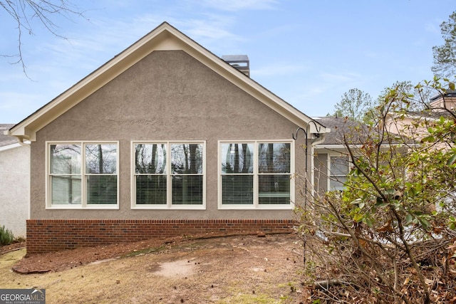 view of side of property with a chimney and stucco siding