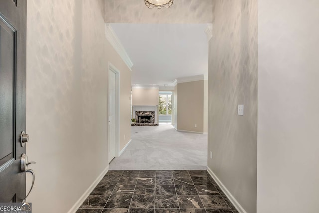 hallway featuring dark carpet, crown molding, and baseboards