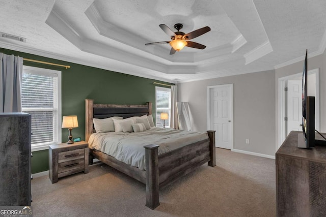 bedroom with carpet flooring, visible vents, baseboards, a tray ceiling, and crown molding