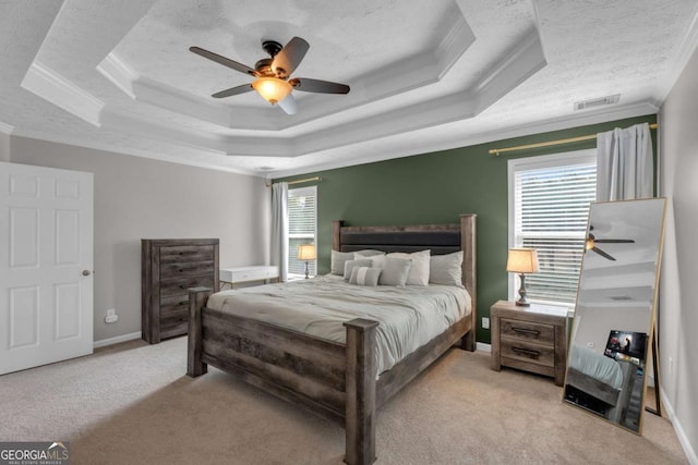 bedroom with carpet flooring, a raised ceiling, visible vents, and crown molding