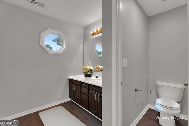 bathroom with toilet, wood finished floors, visible vents, and baseboards