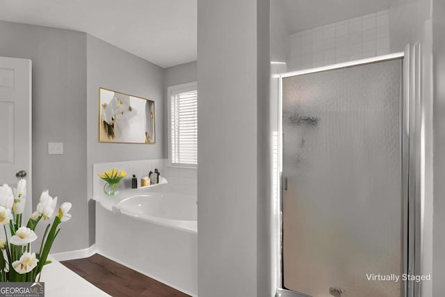 full bathroom with a shower stall, baseboards, a bath, and wood finished floors