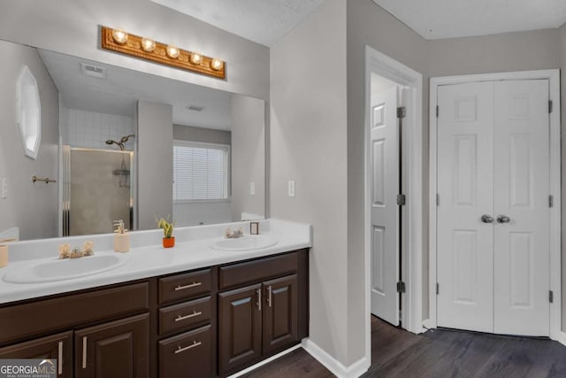 bathroom featuring a shower stall, a sink, and wood finished floors