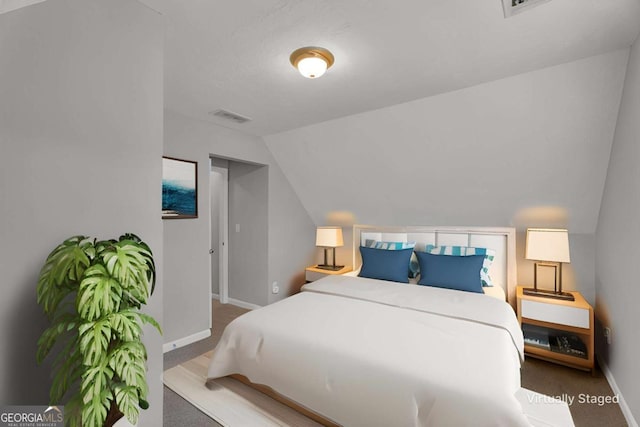 carpeted bedroom with visible vents, vaulted ceiling, and baseboards