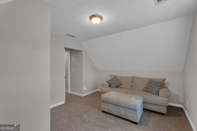 living area featuring baseboards, visible vents, carpet, vaulted ceiling, and a textured ceiling