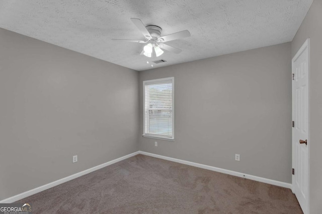 carpeted spare room featuring visible vents, a textured ceiling, baseboards, and a ceiling fan