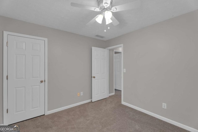 unfurnished bedroom with carpet floors, visible vents, a textured ceiling, and baseboards