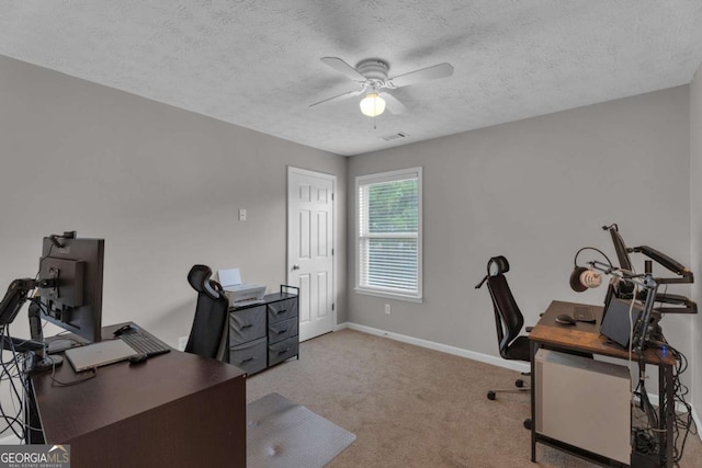 carpeted home office with visible vents, a textured ceiling, baseboards, and a ceiling fan