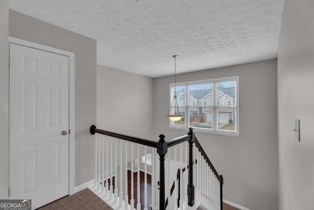 stairway with carpet floors, a textured ceiling, and baseboards