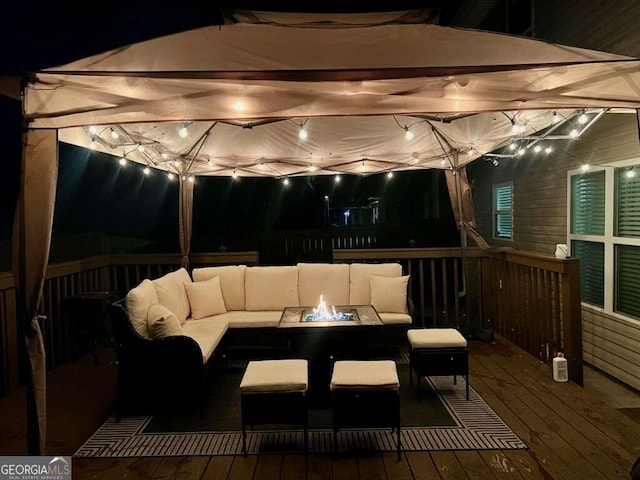 deck at night featuring an outdoor living space with a fire pit