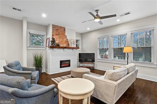 living room with visible vents, a fireplace, and wood finished floors