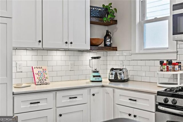 kitchen with appliances with stainless steel finishes, light countertops, white cabinetry, and open shelves