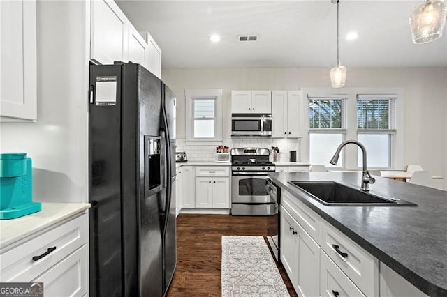 kitchen featuring stainless steel appliances, dark wood-type flooring, a sink, white cabinetry, and decorative backsplash