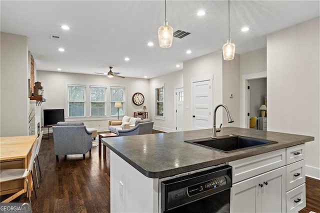 kitchen with black dishwasher, visible vents, dark countertops, dark wood-type flooring, and a sink