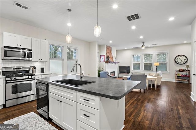 kitchen featuring visible vents, dark wood finished floors, decorative backsplash, appliances with stainless steel finishes, and a sink