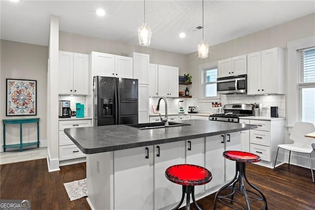 kitchen featuring dark countertops, appliances with stainless steel finishes, dark wood finished floors, and a sink