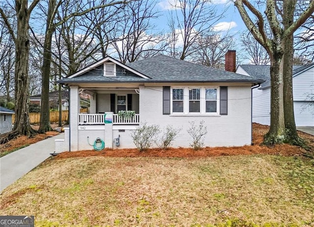 bungalow-style home featuring covered porch, crawl space, brick siding, and a chimney