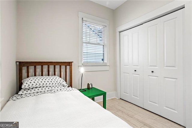 bedroom featuring light wood-type flooring, a closet, and baseboards